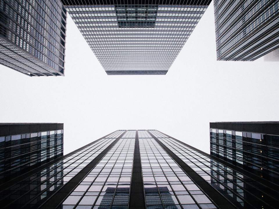 Looking up at modern glass office towers against a pale sky