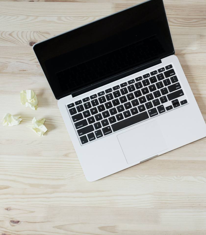 Laptop and coffee cup on a light wooden desk, seen from above