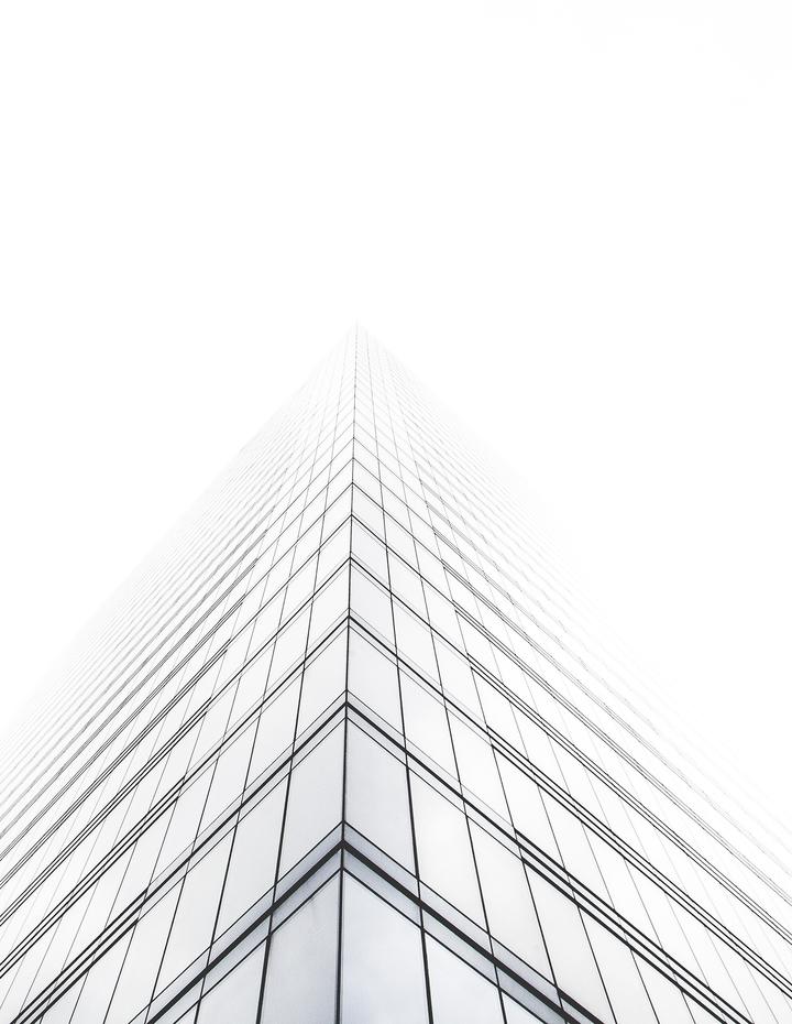 Glass office tower rising into soft white mist