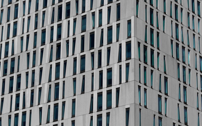 Facade of a modern grey office building with angled windows